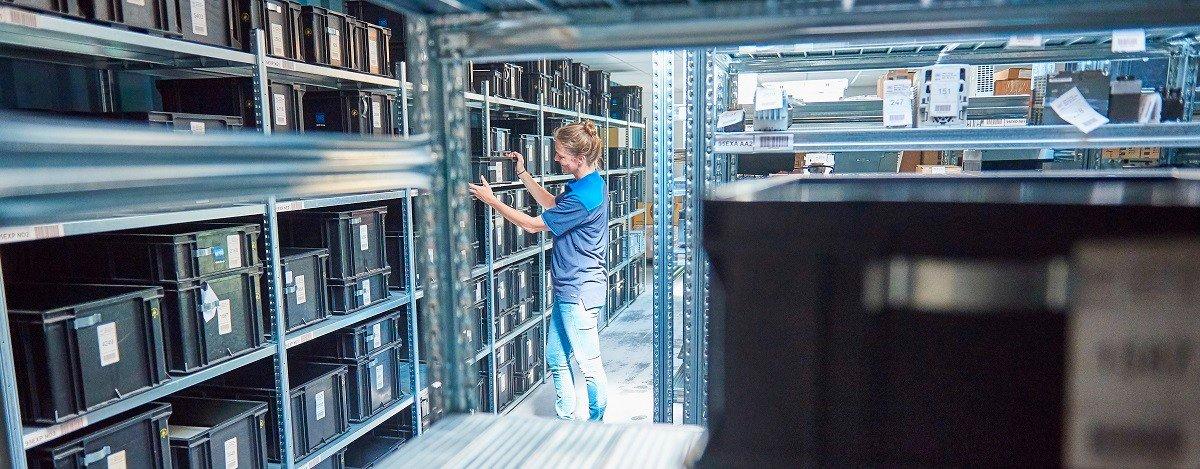 Employee organizing storage bins on shelving in a warehouse.